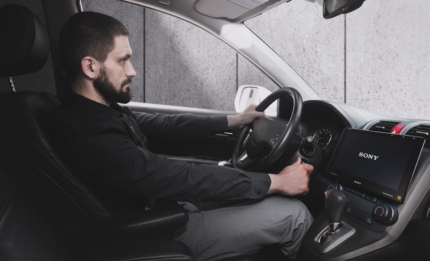 Bild einer Person, die einem Zündschlüssel dreht, mit XAV-9550ES auf dem Armaturenbrett und einem Sony Logo auf dem Bildschirm